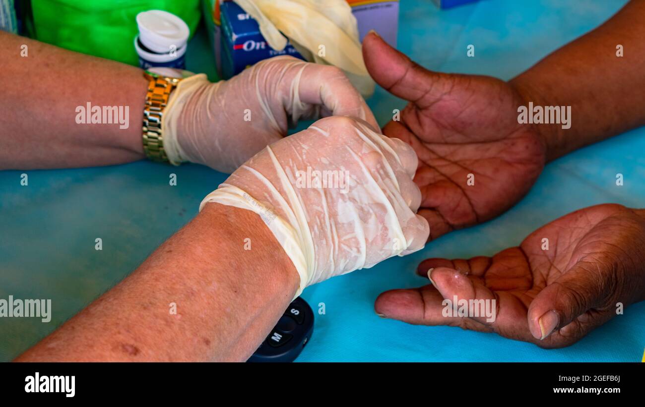 Professionista infermieristico che misura il glucosio di un paziente con diabete mellito Foto Stock Professionista infermieristico che misura il glucosio di un paziente con diabete mellito Foto Stock