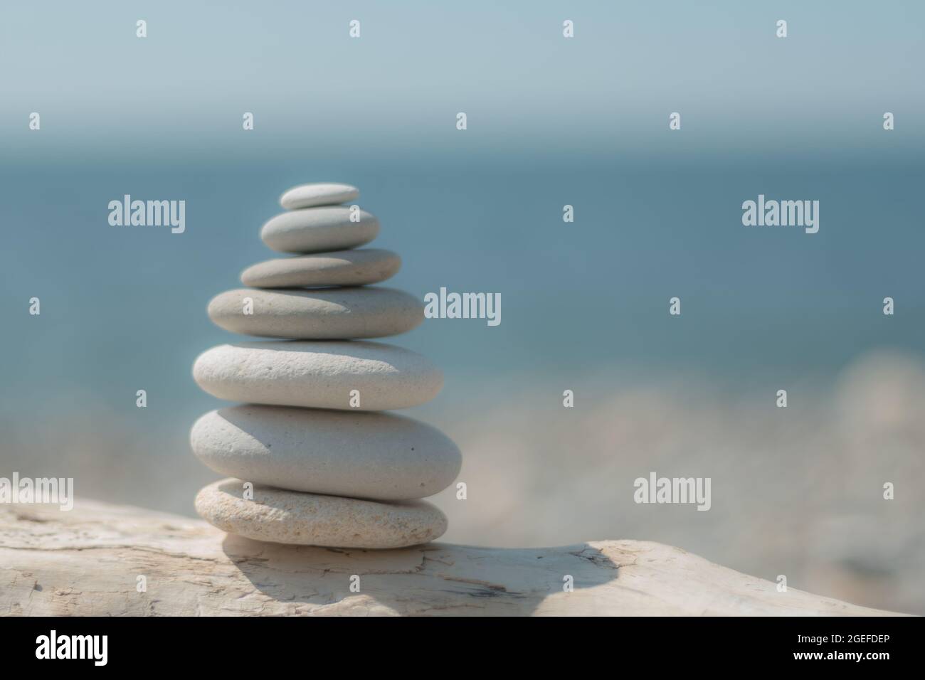 Equilibrata piramide di ciottoli sulla spiaggia in una giornata di sole. Abstract Sea bokeh sullo sfondo. Messa a fuoco selettiva. Pietre Zen sulla spiaggia di mare, meditazione Foto Stock