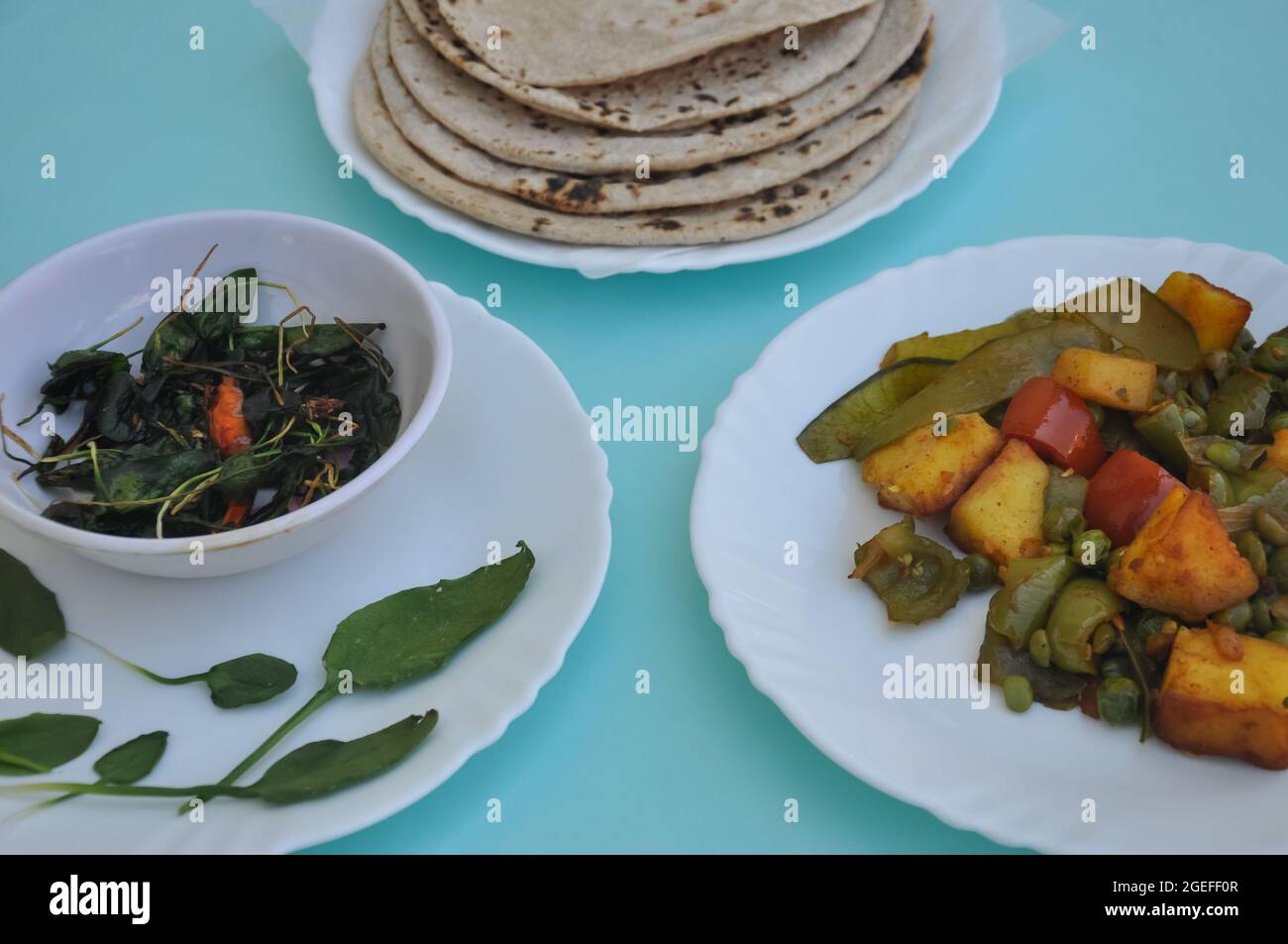 North Indian Food - Matar paneer mix di verdure, saag e roti su piastra bianca con sfondo azzurro Foto Stock