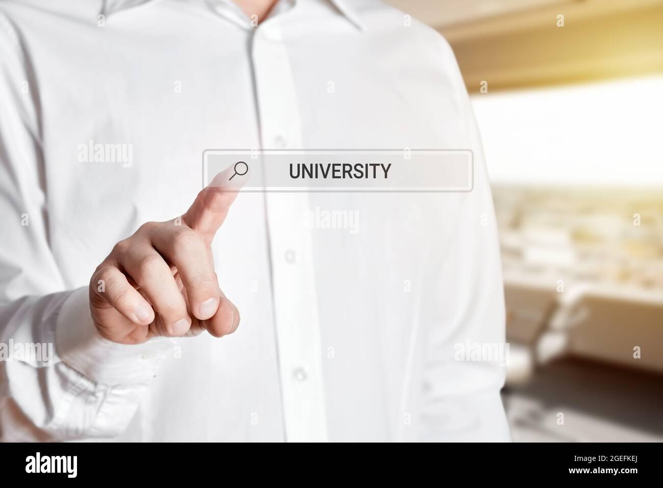 Uomo premere l'icona della barra di ricerca su una schermata virtuale con la parola università. Ricerca online di formazione universitaria su Internet Foto Stock