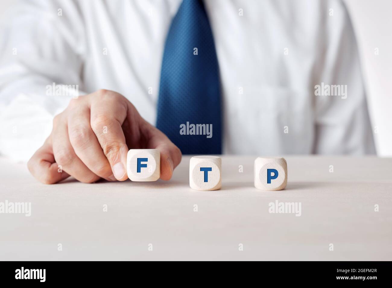 Mano di un uomo d'affari che posiziona i cubi di legno con la parola FTP file Transfer Protocol. Foto Stock