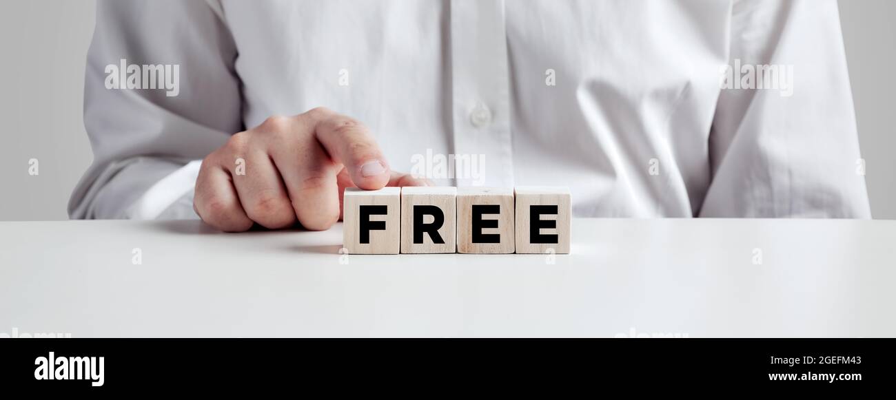 Uomo d'affari che preme il dito sui cubi di legno con la parola libera. Promozione aziendale gratuita, prova gratuita o concetto di consegna. Foto Stock