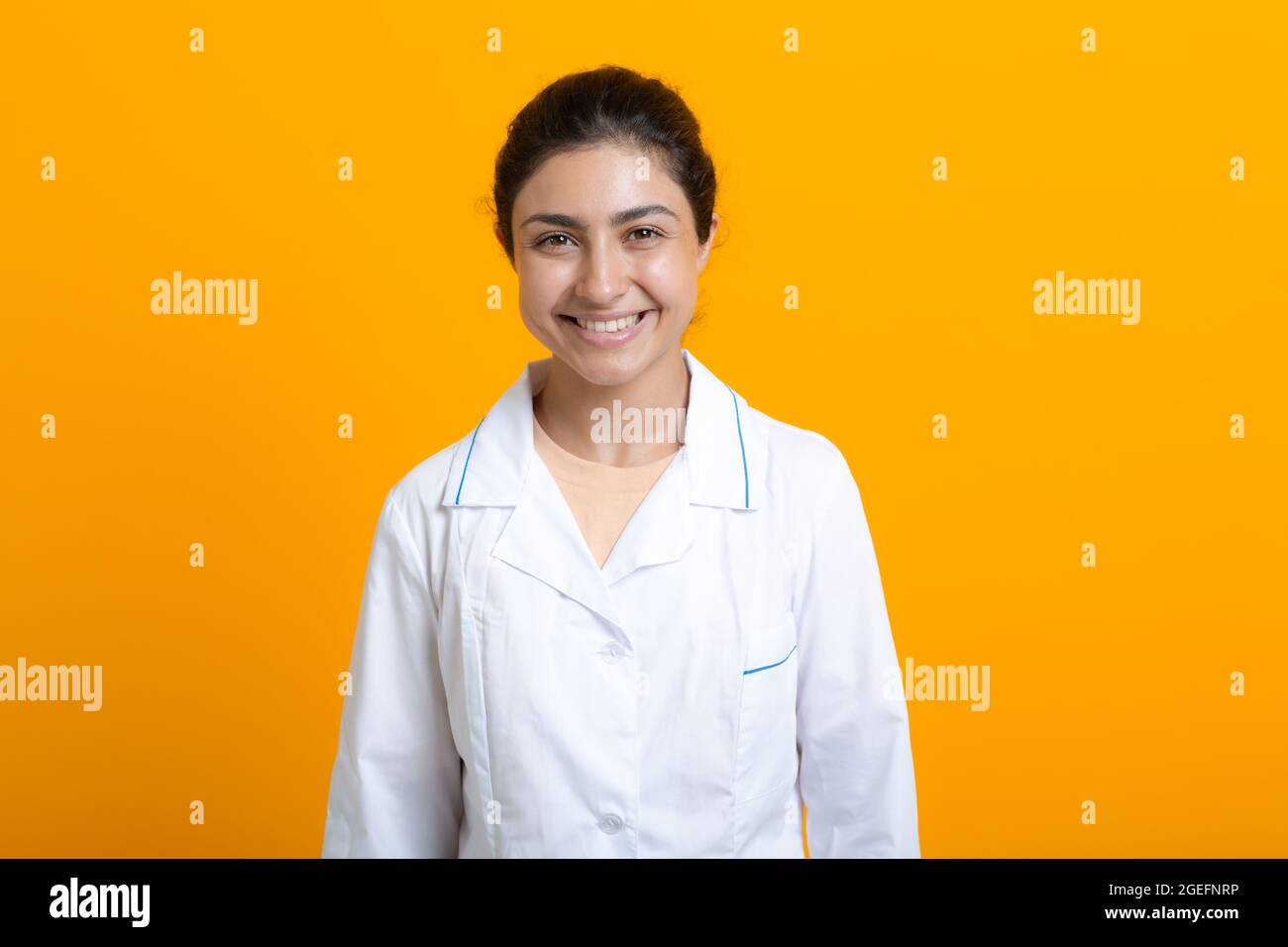 Ritratto di medico indiano donna in abito medico bianco isolato su sfondo giallo. Foto Stock