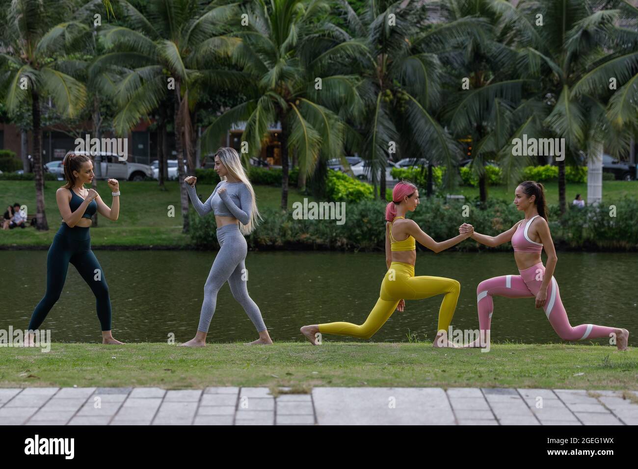 Quattro donne piuttosto giovani che fanno esercizi di fitness nel parco invece di andare in palestra. Concetto di esercizio per una buona forma. Concetto di stile di vita sano. Foto Stock