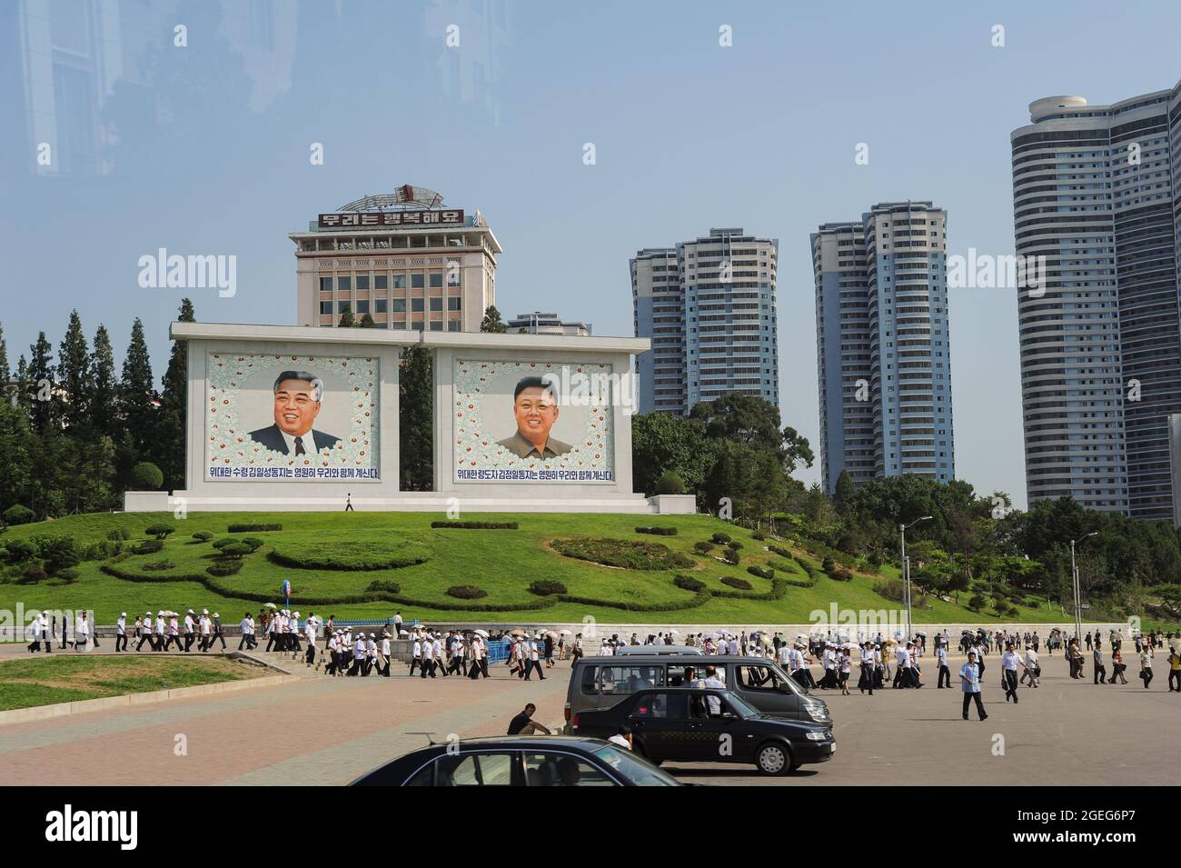 08.08.2012, Pyongyang, Corea del Nord, Asia - i pedoni passano davanti a due giganteschi dipinti a tavola raffiguranti i ritratti dei capi della Corea del Nord. Foto Stock