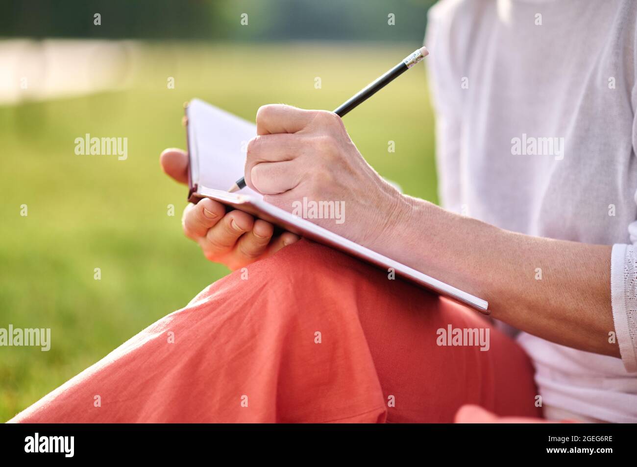 Womans scrivere a mano con la matita in taccuino Foto Stock