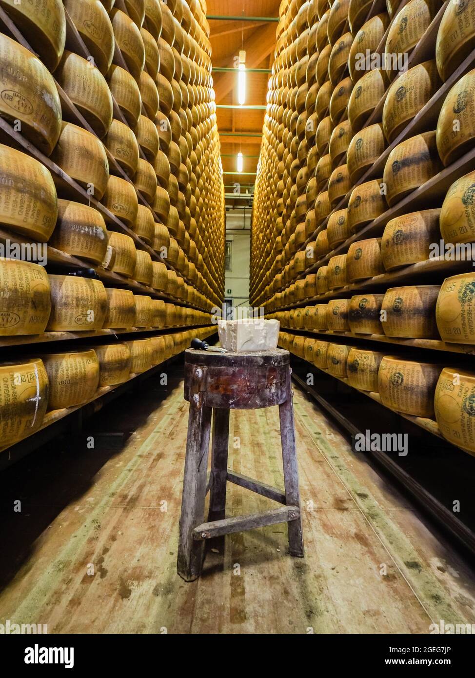 MONTECCHIO, ITALY - Jan 18, 2021: Un colpo verticale di una fabbrica piena  di ruote di formaggio con un piccolo sgabello in legno al centro Foto stock  - Alamy