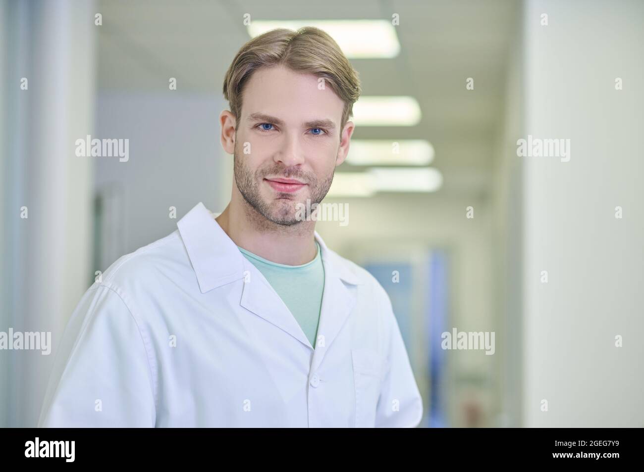 Medico tranquillo e attraente in posa per la fotocamera sul posto di lavoro Foto Stock