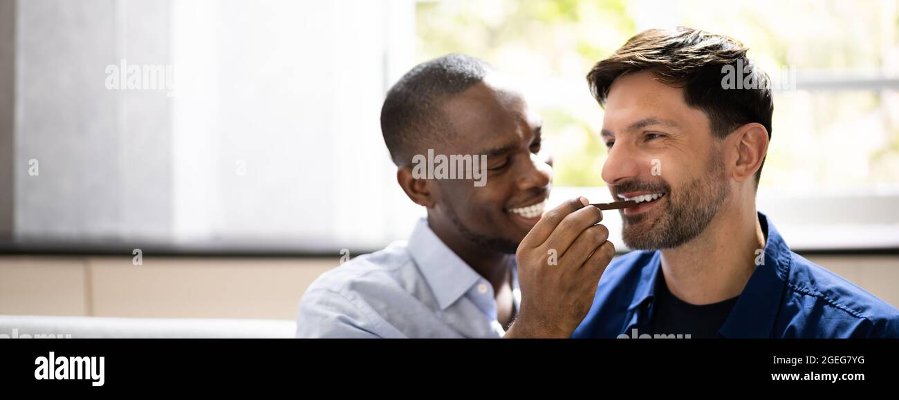 Data romantica. Happy Gay coppia che condividono snack Foto Stock