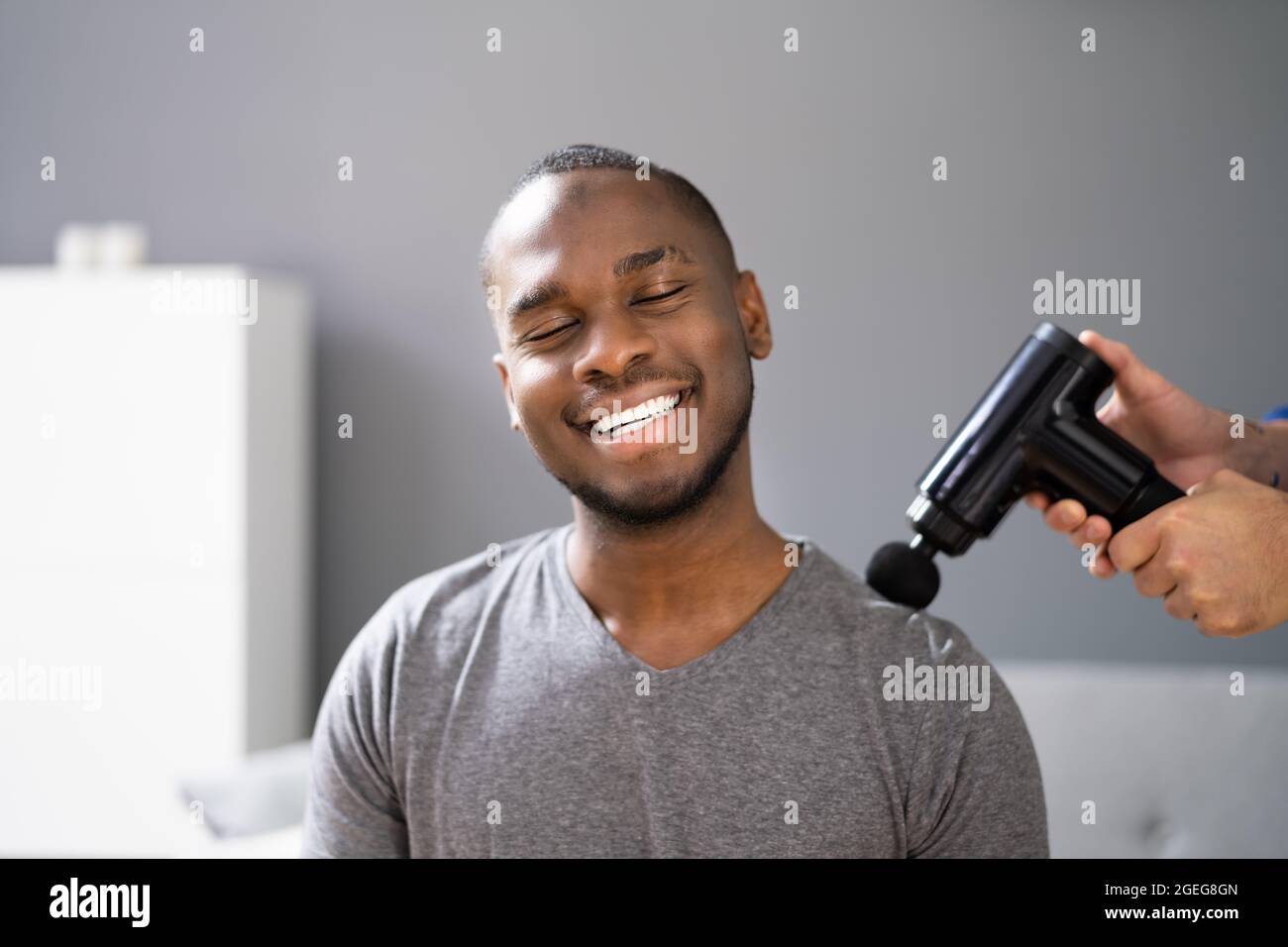 Terapia di recupero delle spalle usando la pistola di massaggio o la macchina Foto Stock