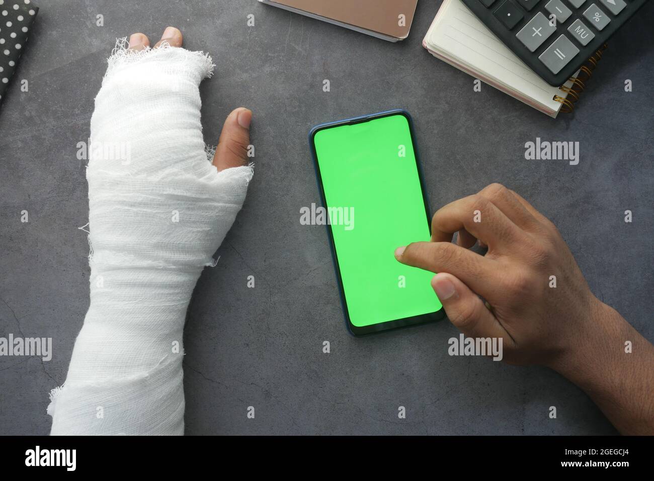 ferita mano dolorosa con bendaggio e l'uso di smartphone sul tavolo Foto Stock