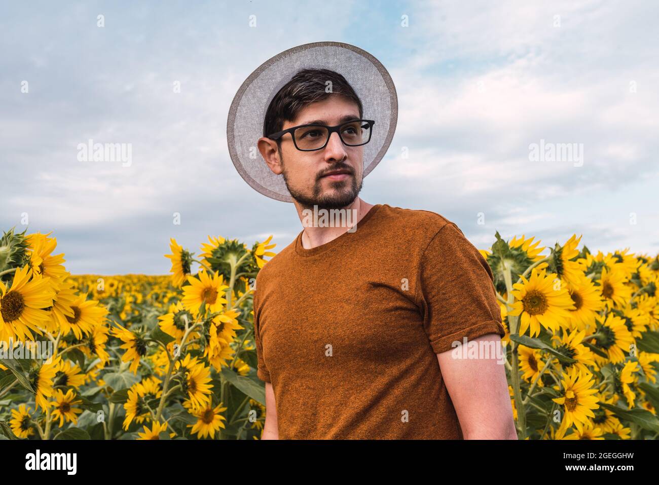 Giovane uomo con cappello e bicchieri in un campo di girasoli Foto stock -  Alamy