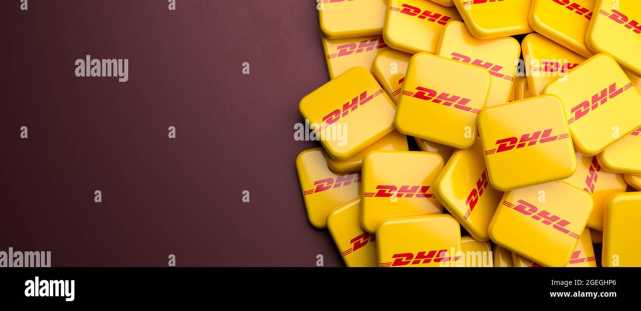 Logo del corriere, consegna pacchi e servizio di posta espresso DHL (appartenente alla società tedesca di logistis Deutsche Post) su un mucchio su un tavolo. COP Foto Stock