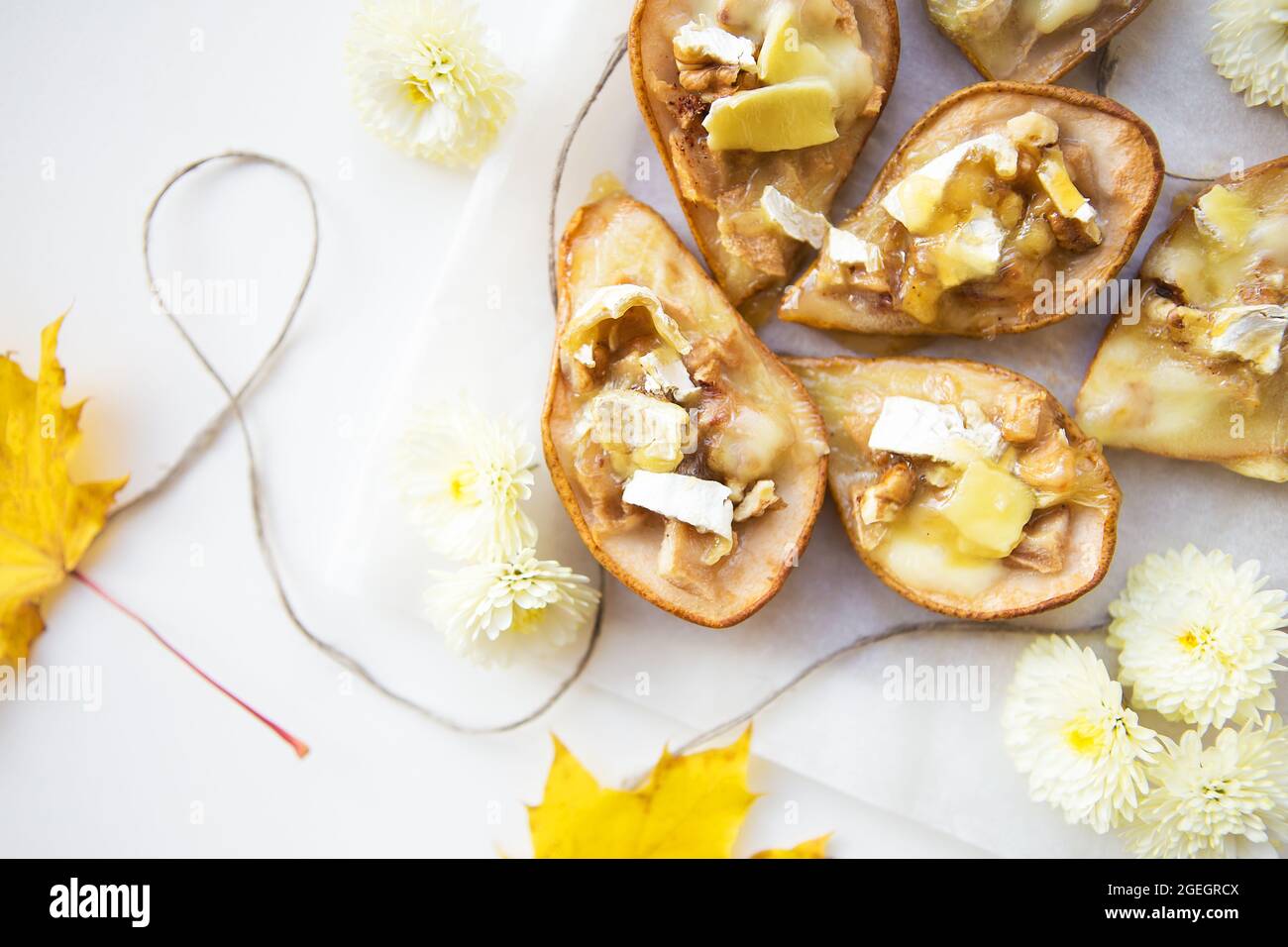pere al forno con formaggio brie e noci sullo sfondo delle foglie gialle  d'autunno, primo piano Foto stock - Alamy