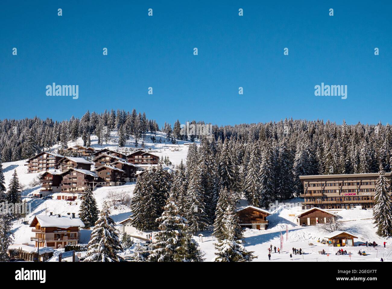 La Clusaz (Alpi, Francia centro-orientale): Paesaggio montagnoso con chalet innevati nella stazione sciistica, vista dalla strada che conduce alla pa Foto Stock