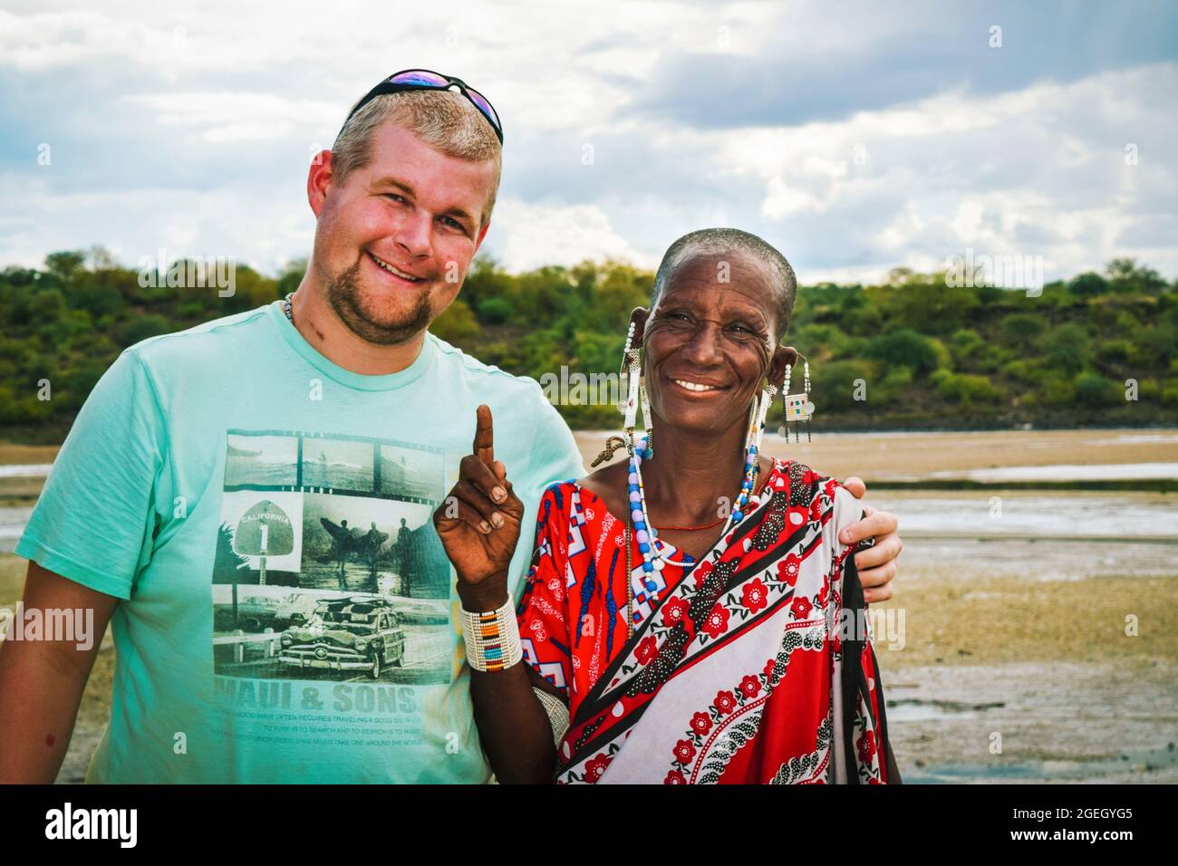 Una donna masai in abiti tradizionali pone per una foto con un turista Foto Stock