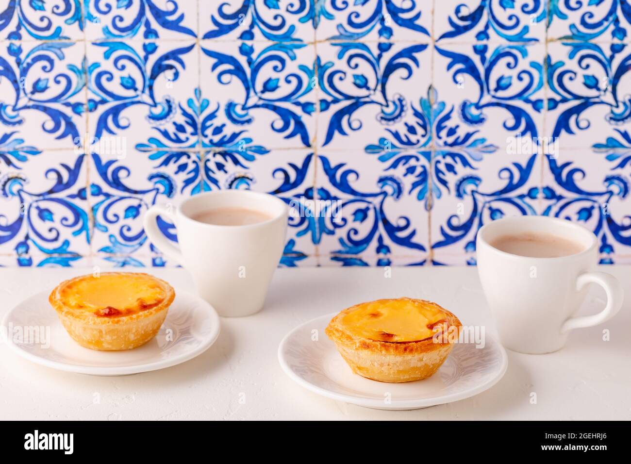 Freccette d'uovo, dessert tradizionale portoghese, pastello de nata/pastello de belem. Sfondo piastrellato Azulejo. Foto Stock