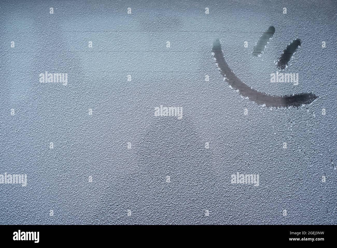 Un'emoticon da disegno su un finestrino innevato Foto Stock