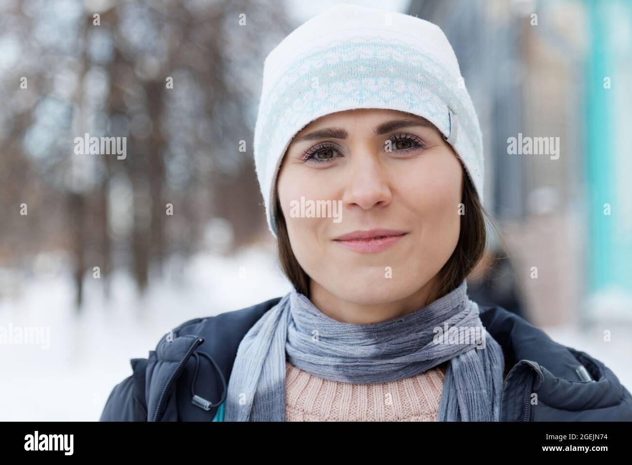 Ritratto di giovane donna che guarda la macchina fotografica in strada d'inverno su sfondo sfocato Foto Stock