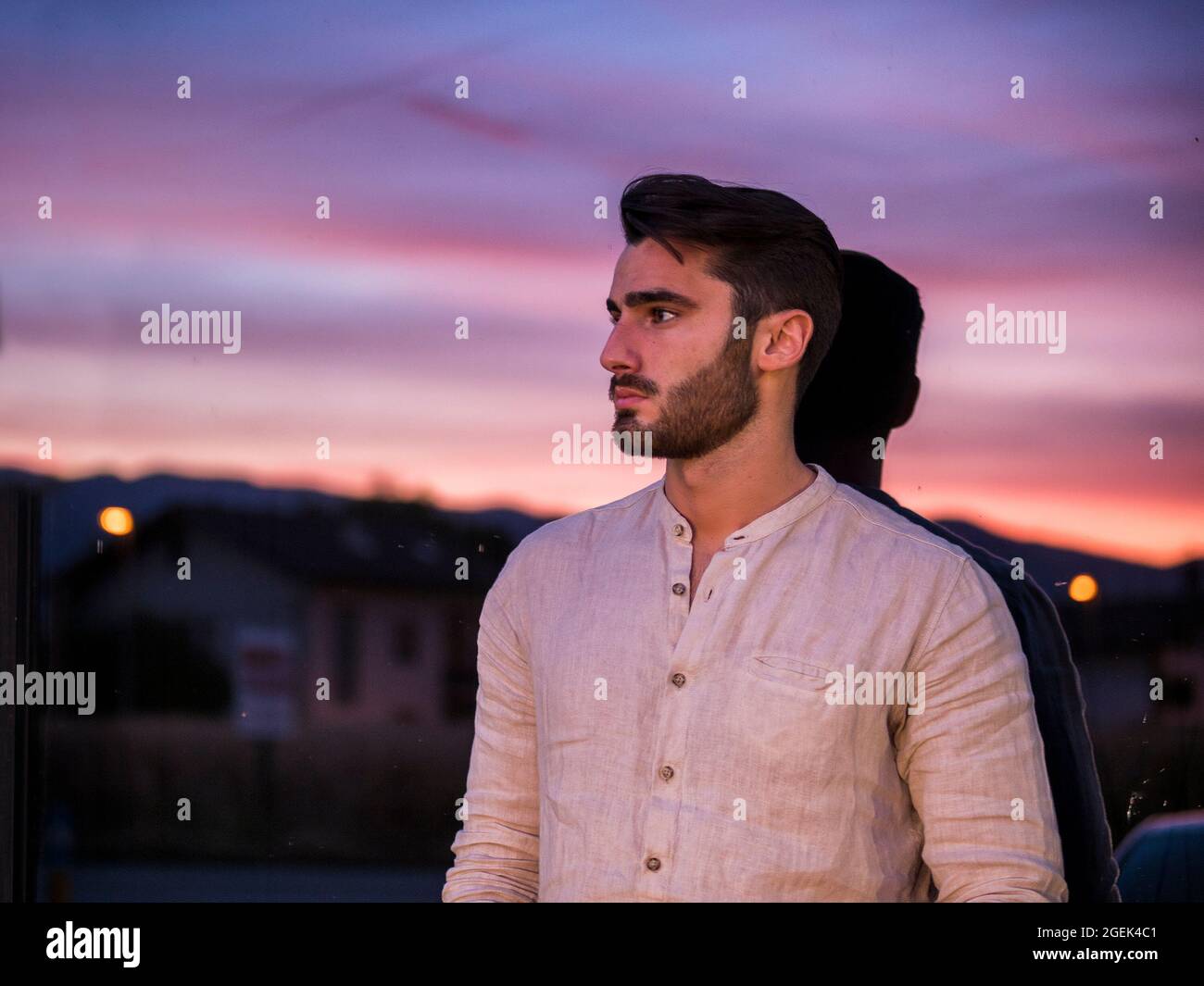 Attraente giovane uomo in piedi sullo sfondo del tramonto del sole Foto Stock