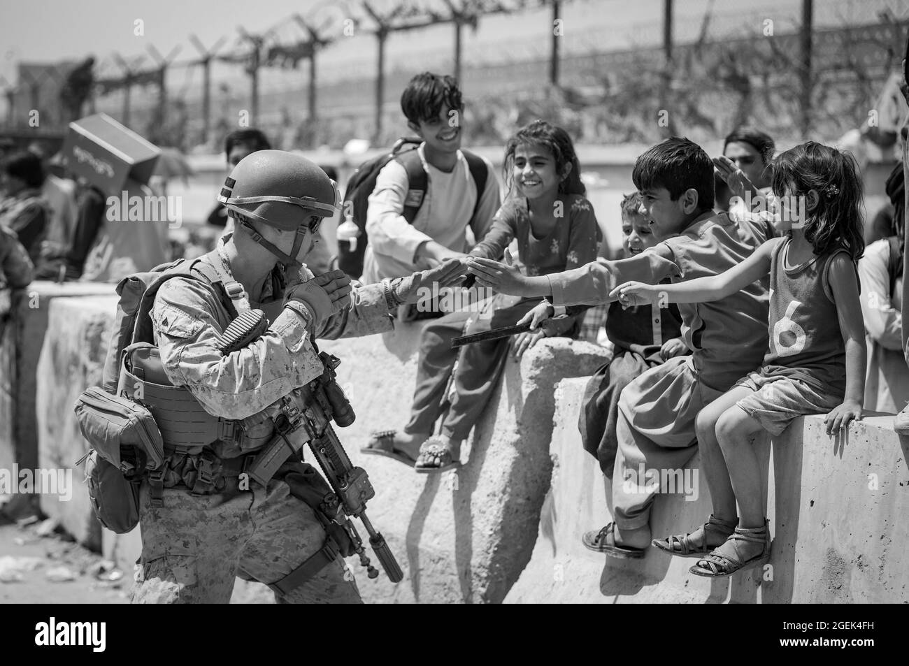 Una Marina con Special Purpose Marine Air-Ground Task Force-Crisis Response-Central Command (SPMAGTF-CR-CC) gioca con i bambini in attesa di processo durante un'evacuazione all'Aeroporto Internazionale Hamid Karzai, Kabul, Afghanistan, 20 agosto. I membri del servizio degli Stati Uniti stanno assistendo il Dipartimento di Stato con un prelievo ordinato di personale designato in Afghanistan. (STATI UNITI Foto del corpo marino di Sgt. Samuel Ruiz). Foto Stock