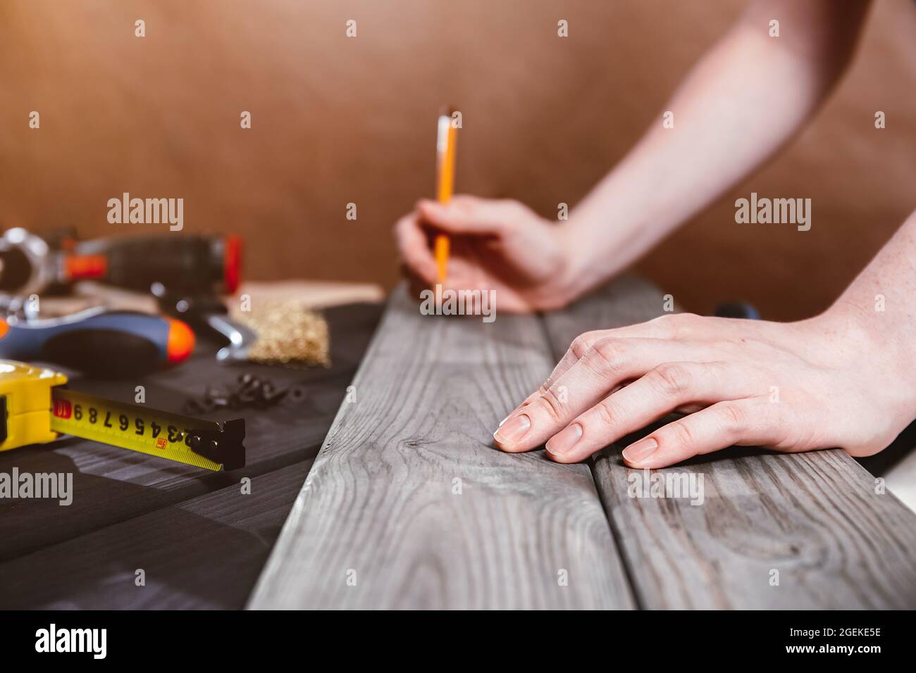 Riparazione, costruzione e concetto domestico - primo piano delle mani femminili che misurano i pannelli di legno. Il carpentiere professionale effettua misurazioni accurate con una t. Gialla Foto Stock