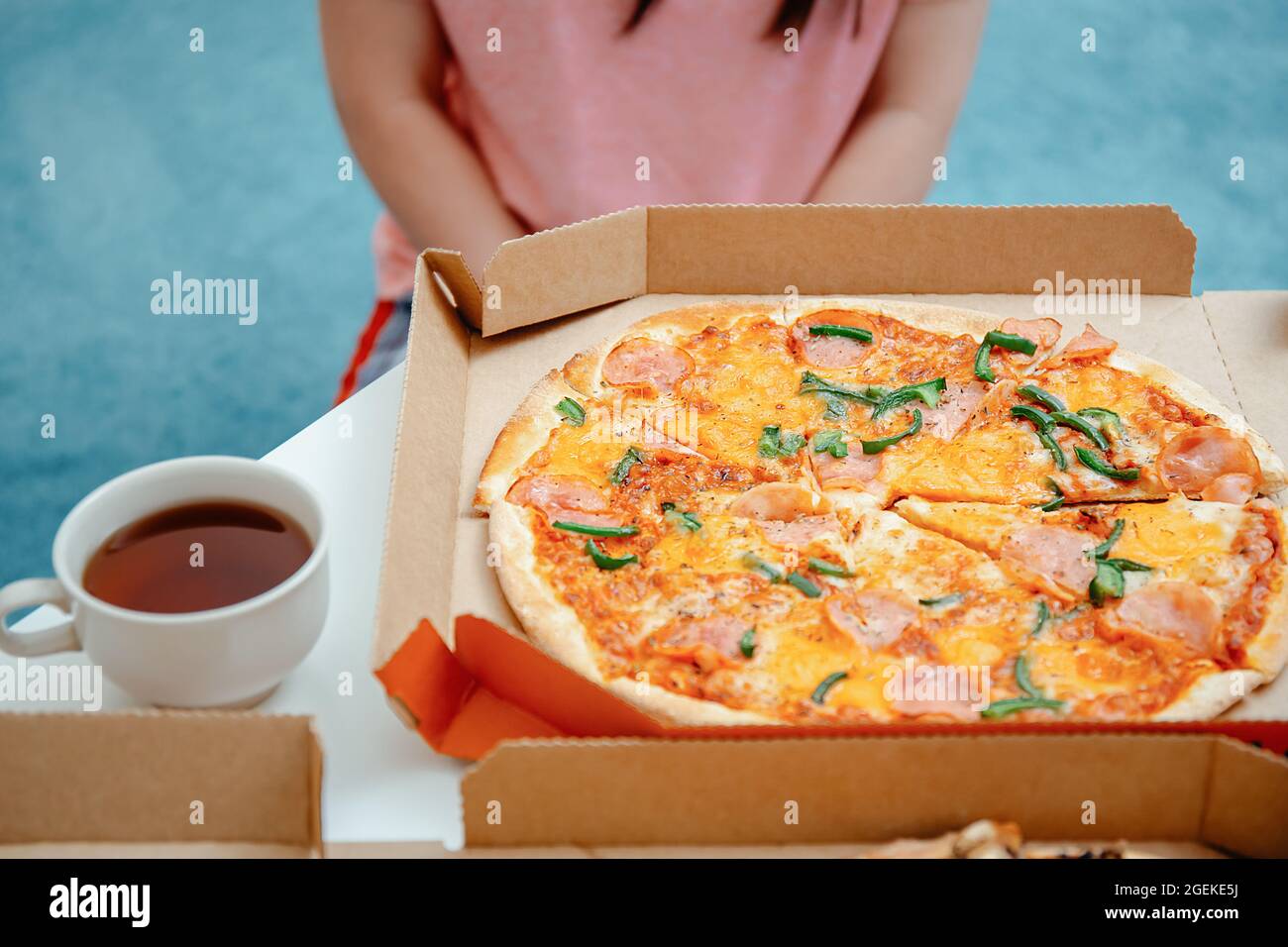 Giovane donna infelice che guarda la pizza in scatola pizza. Dieta per adulti e rifiuto da glutine, farina di grano e panificio concetto. Infrangere le regole di dieta Foto Stock