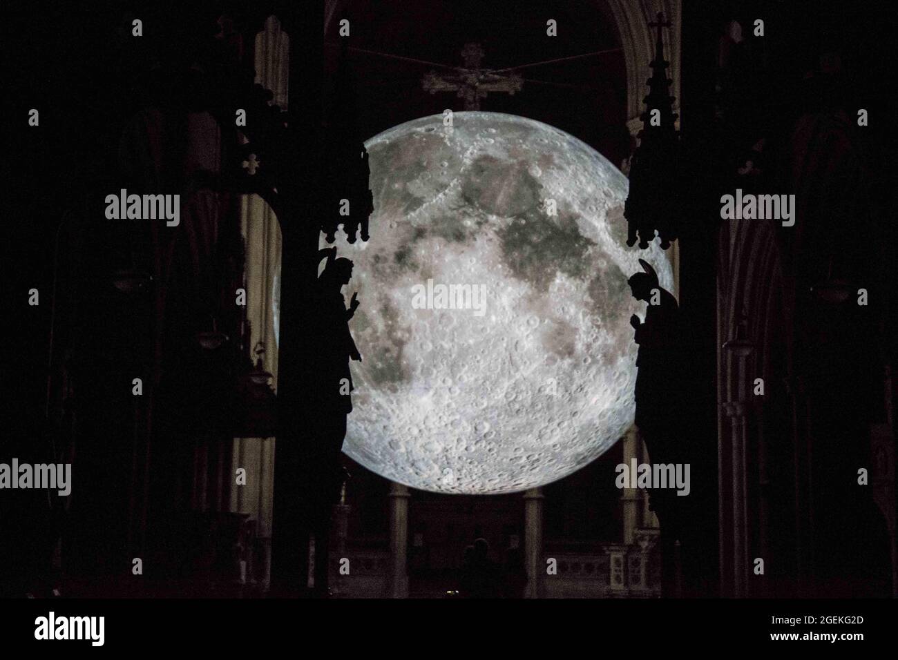 Londra UK 20 ago 2021 Angel Gabriel (L) e Mary (R) hanno scolpito contro l'artista britannico Luke Jerram Moon. Come parte del Kensington Chelsea Festival .Museum of the Moon è un'opera d'arte itinerante dell'artista britannico Luke Jerram. Con un diametro di sette metri, la luna presenta immagini NASA dettagliate a 120 dpi della superficie lunare. Mostra alla chiesa di San Giovanni Battista in Shepherd's Bush. Paul Quezada-Neiman/Alamy Live News Foto Stock