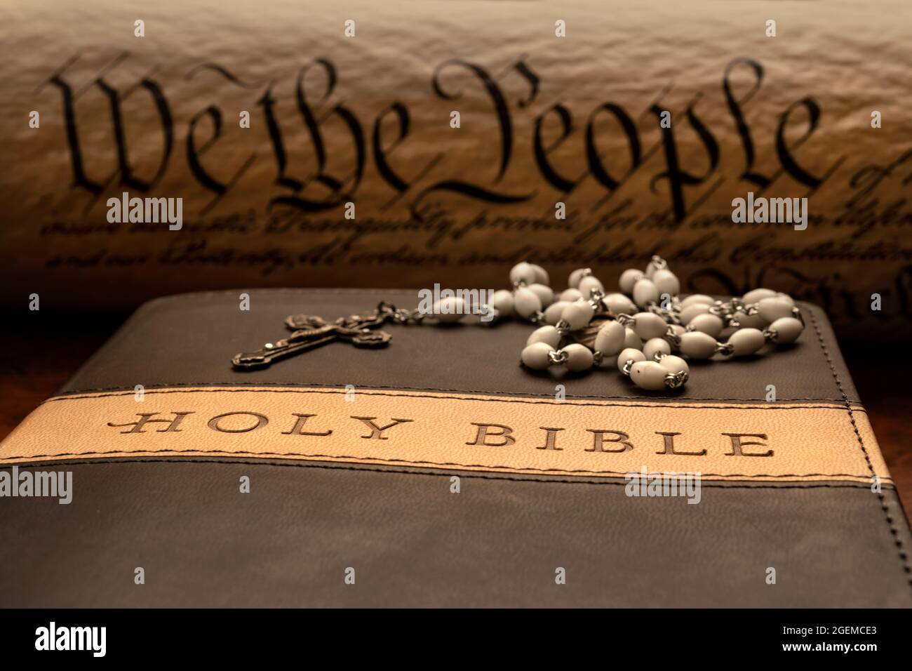 Primo piano di una croce religiosa in cima alle pagine di una bibbia con la costituzione sullo sfondo. Foto Stock