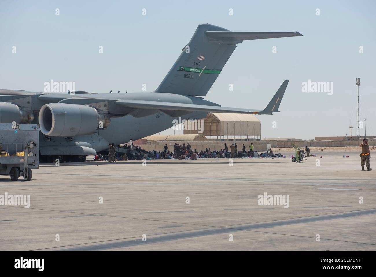 Gli evacuati qualificati attendono sotto l'ala di C-17 Globemaster ll prima di poter lavorare sull'aeromobile, 20 agosto 2021. Nell'ambito dell'operazione Allies Refuge, i cittadini afghani hanno evacuato l'aeroporto internazionale Hamid Karzai di Kabul, a bordo di aerei militari. (STATI UNITI Air Force foto di Airman 1a classe Kylie Barrow) Foto Stock