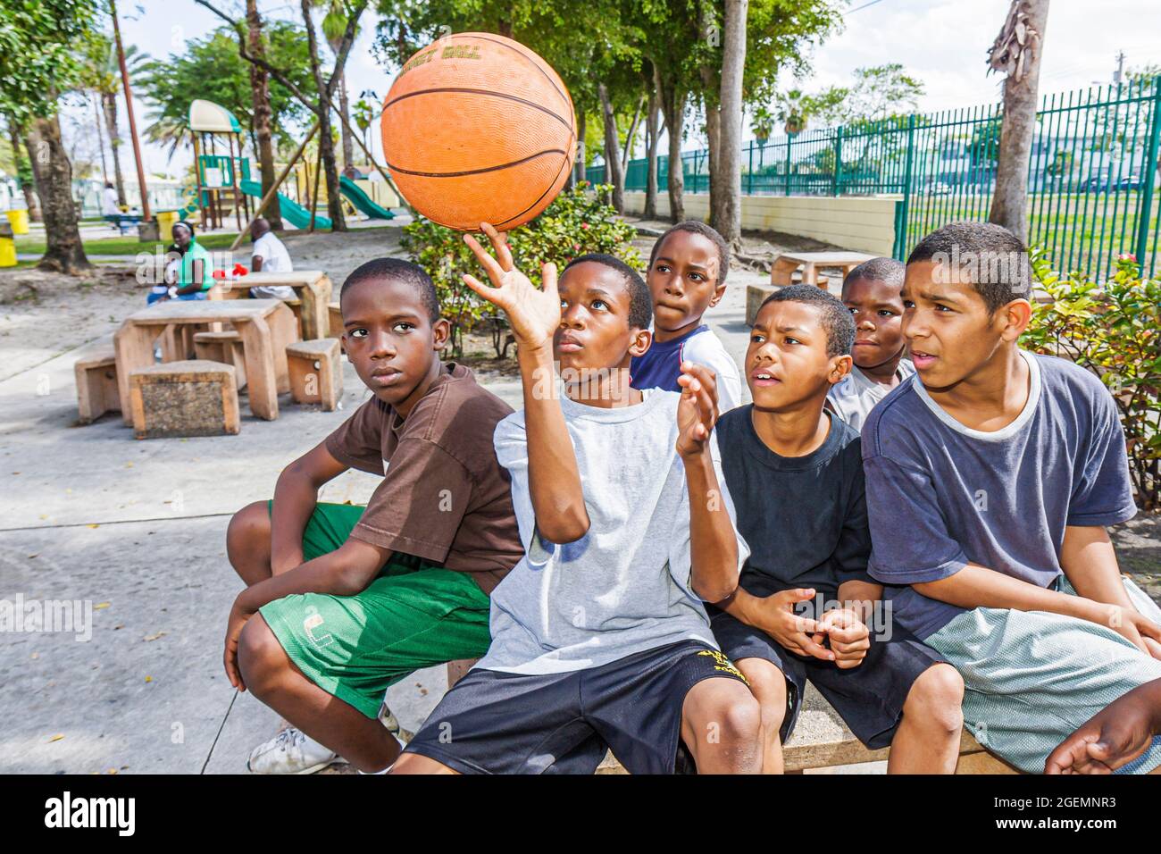 Miami Florida,Liberty City African Square Park Inner city,Black boys maschio bambini gruppo amici parco giochi,mostrando off basket bilanciamento spin Foto Stock