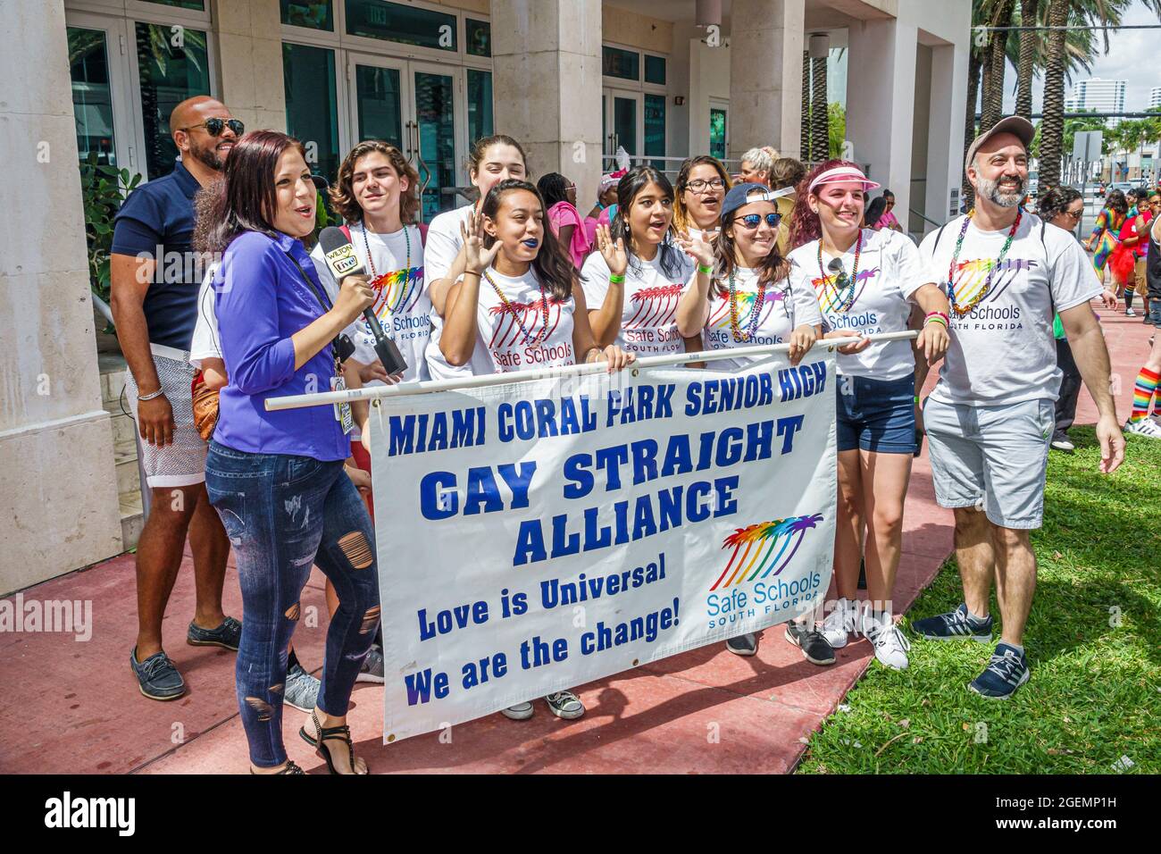 Miami Beach Florida, LGBTQ LGBT Pride Parade partecipanti, gay Straight Alliance studenti ispanici in possesso di banner, donna reporter media reporting Foto Stock