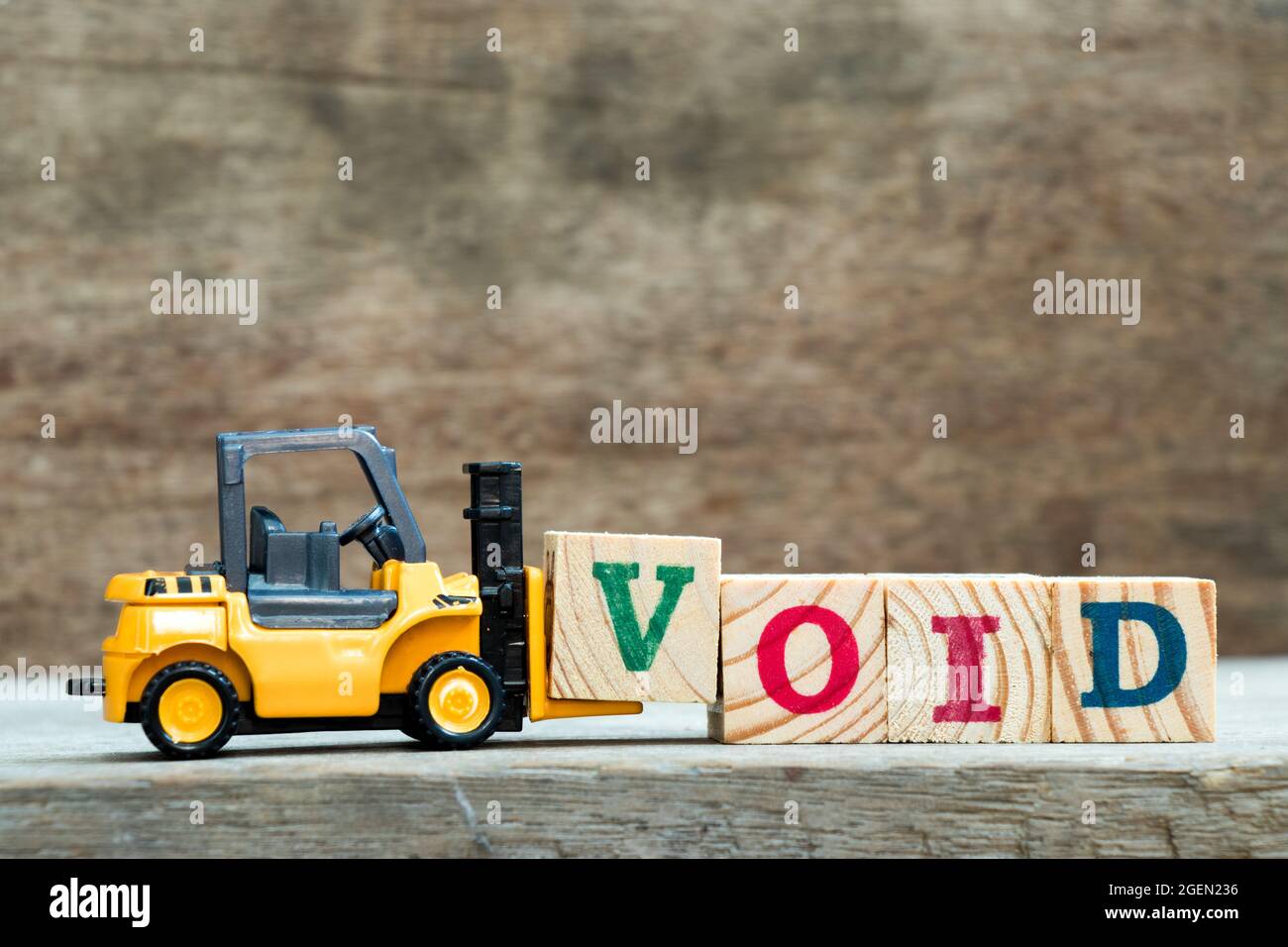 Carrello giocattolo giallo tenere il blocco di lettera V per completare la parola vuoto su sfondo di legno Foto Stock