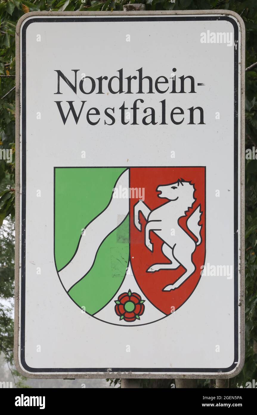 Hennef, Germania. 20 ago 2021. Un cartello stradale con stemma di stato si trova al confine tra Renania settentrionale-Vestfalia e Renania-Palatinato. La Renania settentrionale-Vestfalia ha 75 anni quest'anno. Il fiume a sinistra dello stemma rappresenta il Reno e quindi la Renania. Il cavallo della Westfalia sta per la Westfalia e la rosa di Lippe è il simbolo della regione di Lippe. (Al pacchetto tematico dpa '75 anni di Renania Settentrionale-Vestfalia' dal 21.08.2021) credito: Oliver Berg/dpa/Alamy Live News Foto Stock