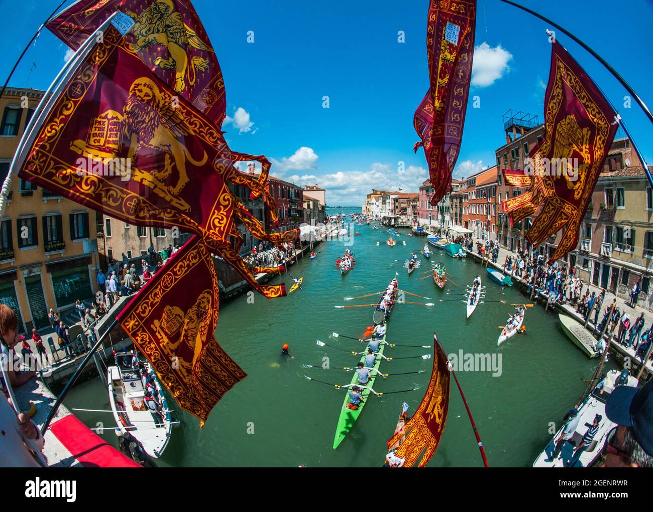 Splendida vista su edifici costieri e barche a remi dal ponte con bandiere di Venezia Foto Stock