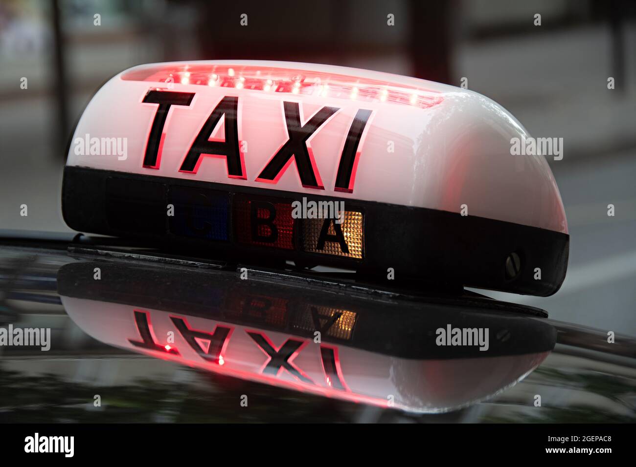 Cartello illuminato sul tetto con la parola TAXI attaccata a un veicolo in una strada di Parigi, Francia Foto Stock