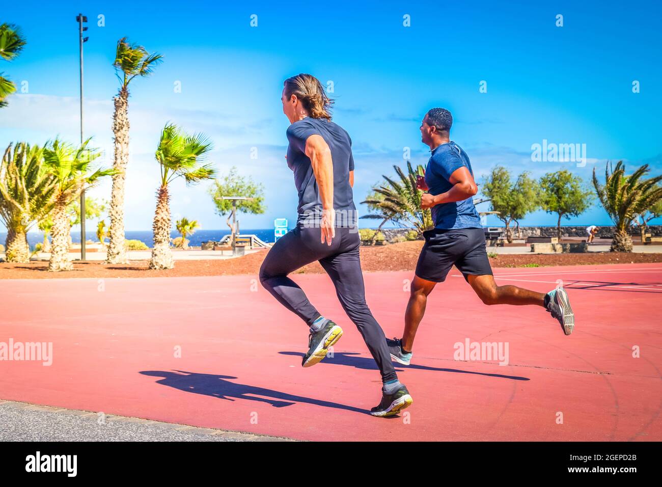 Due simpaticissimi sportivi sani e sicuri che corrono all'aperto in spiaggia Foto Stock