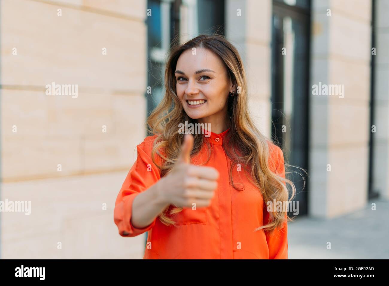 Donna sorridente nella sua trentenne e che mostra i pollici in su Foto Stock