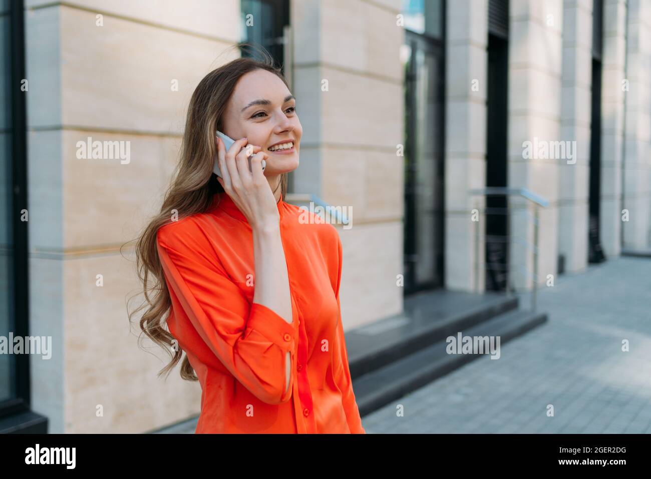 Donna di trent'anni comunica su un telefono cellulare in città Foto Stock