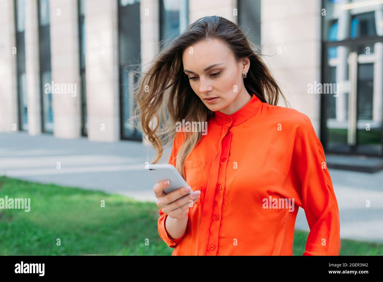 Donna di trent'anni che guarda attentamente il suo smartphone mentre cammina per la città Foto Stock