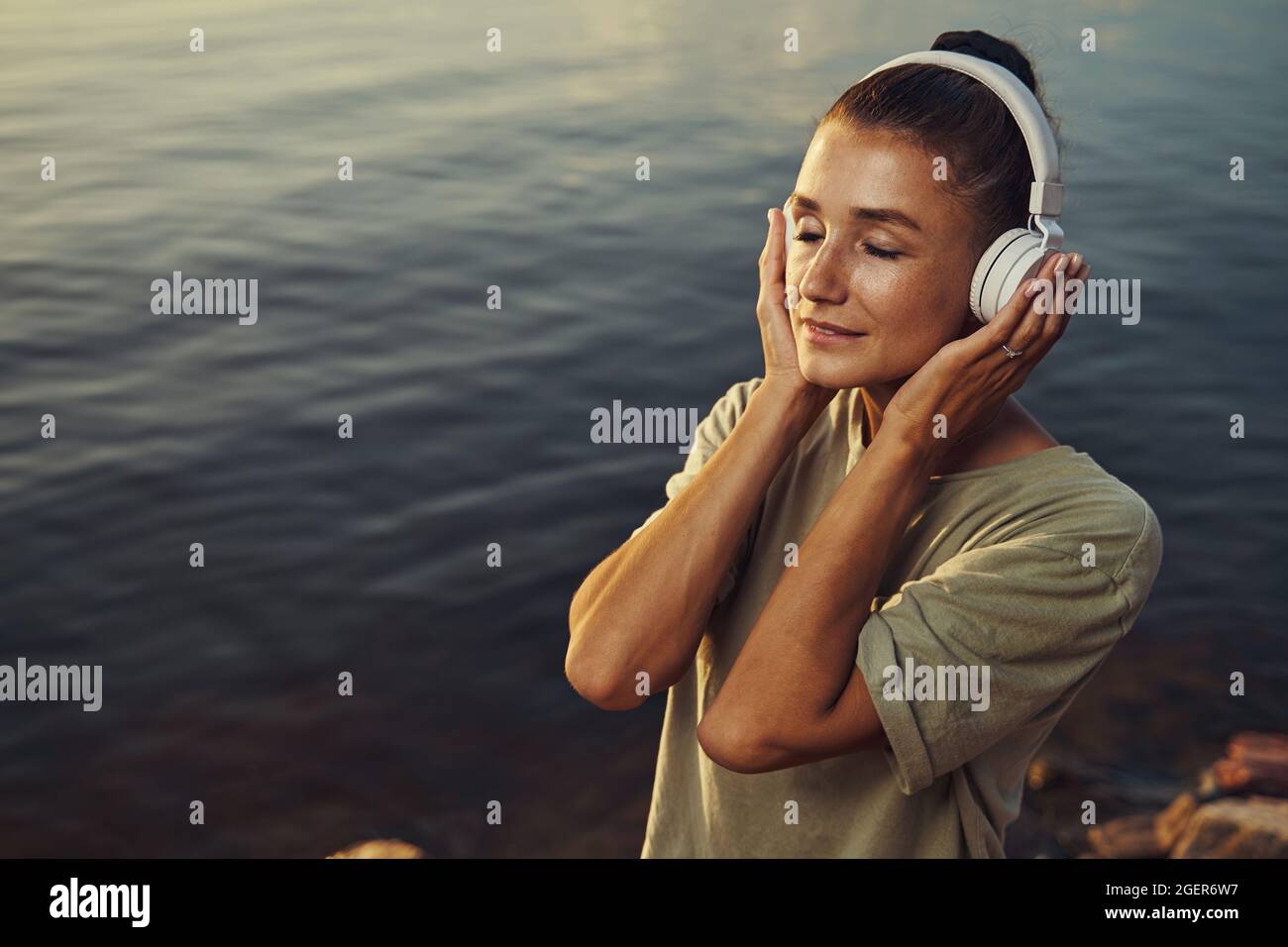 Femmina che si perde nella musica sul lago Foto Stock