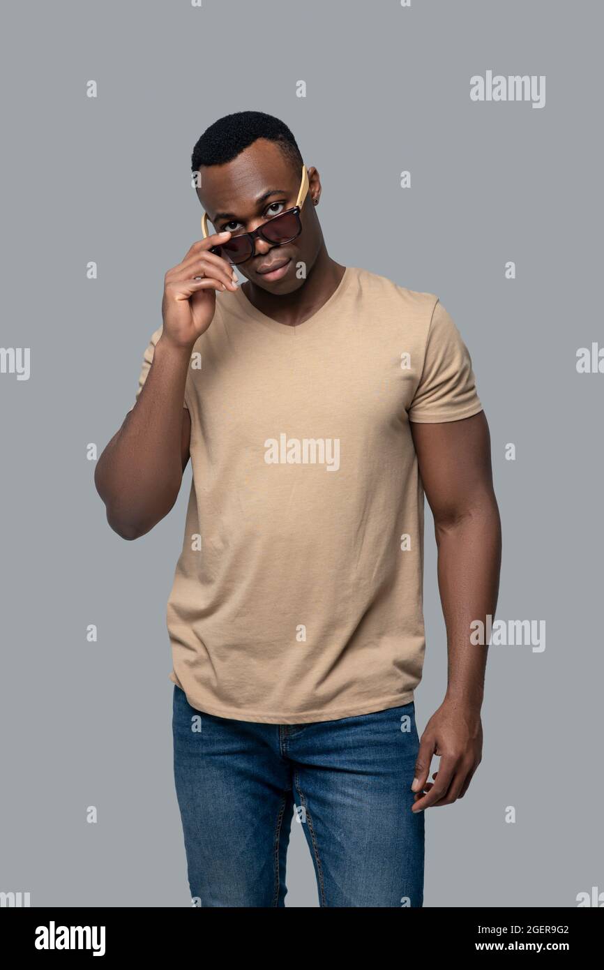 Giovane uomo con pelle scura in maglietta beige che ha un aspetto deciso Foto stock Alamy