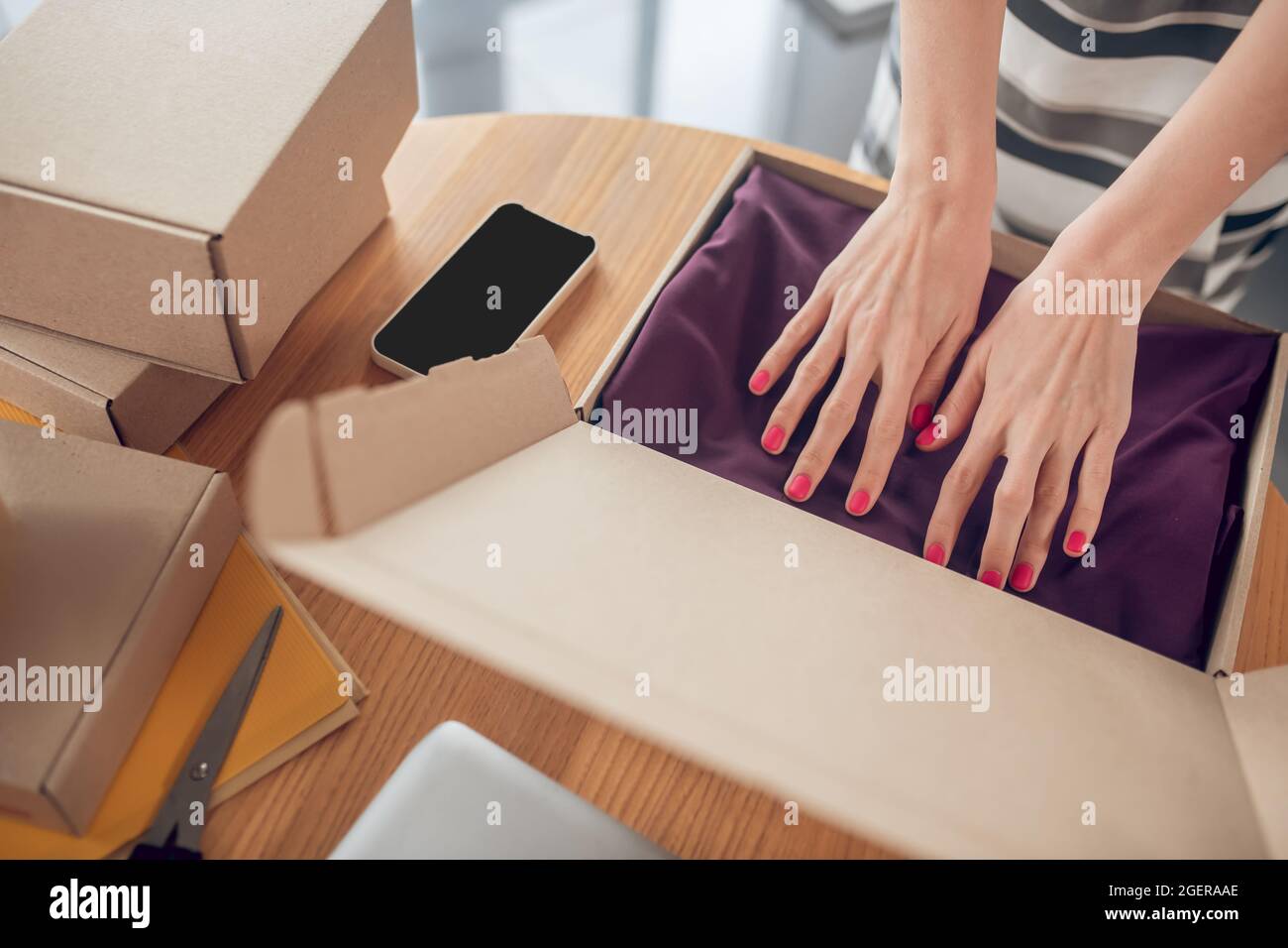 Venditore femminile che organizza un abito in un pacchetto Foto Stock