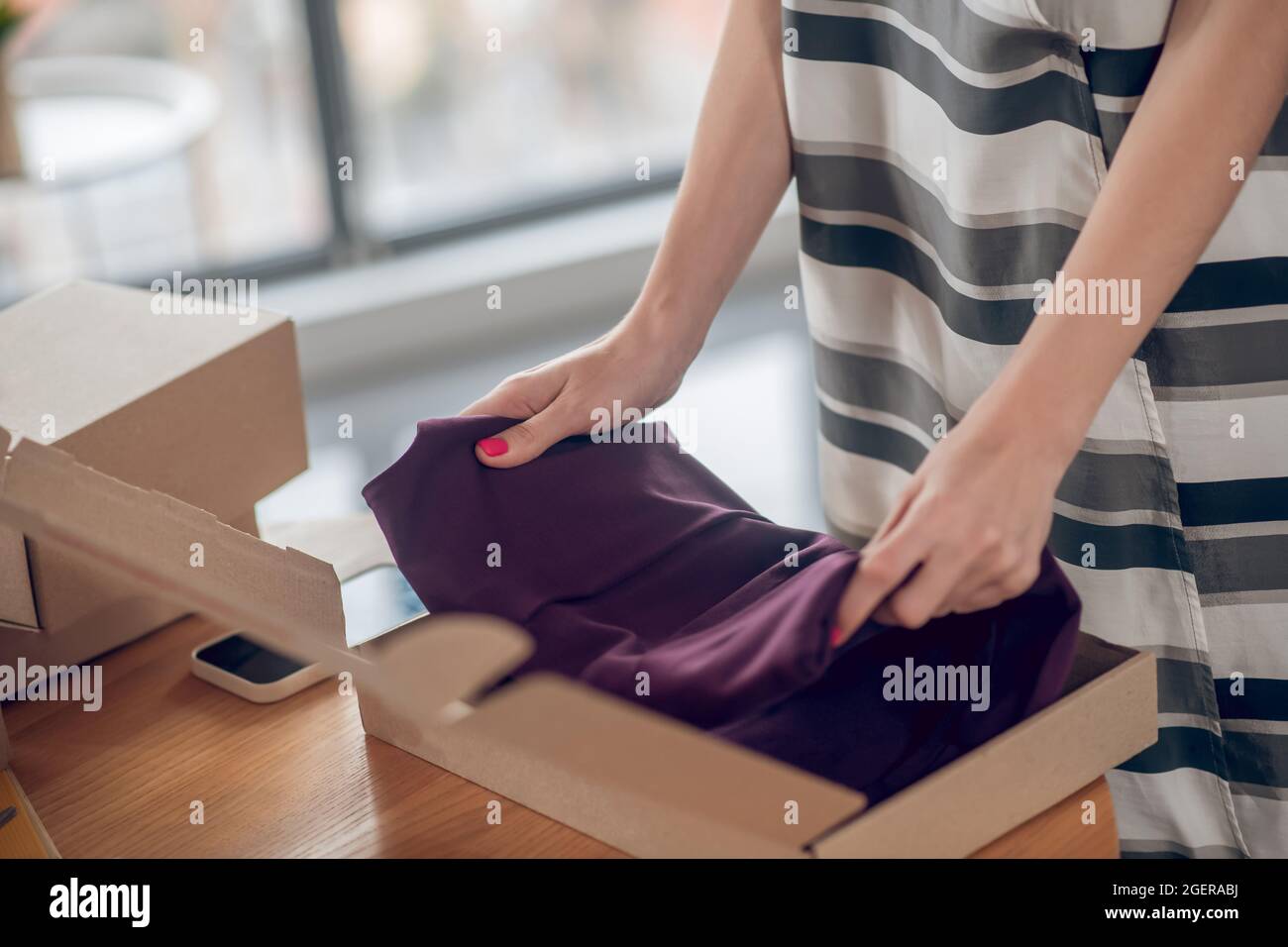 Venditore esperto che prepara un indumento per la spedizione Foto Stock