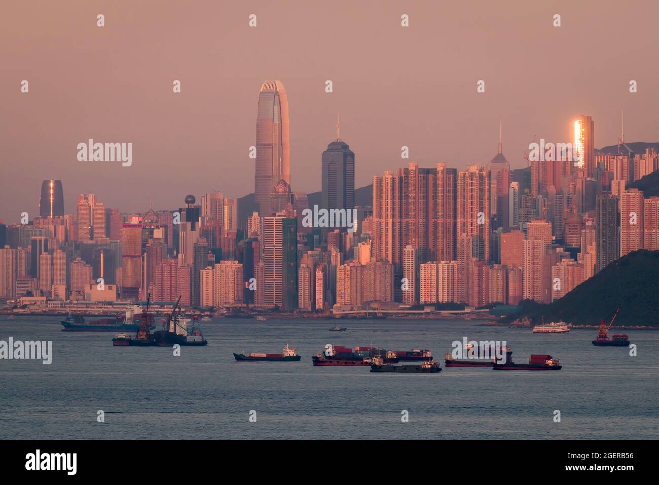 Il tramonto si riflette in un alto blocco di appartamenti a Mid-level, con i grattacieli di Central, Isola di Hong Kong, nella luce rosa del tramonto Foto Stock