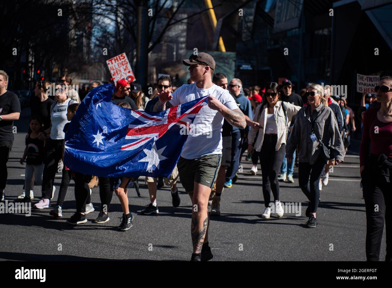 Melbourne, Australia. 21 agosto 2021. Un uomo con una bandiera australiana si sposa con i manifestanti anti di blocco mentre inghiottiscono le strade di Melbourne nelle loro migliaia. Credit: Jay Kogler/Alamy Live News Foto Stock