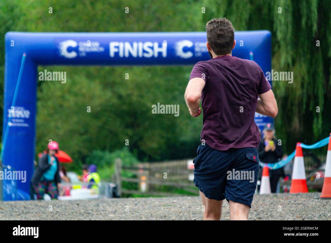 Un uomo che corre la corsa di Ricerca del cancro per la vita su Hampstead Heath si avvicina al traguardo. Foto Stock