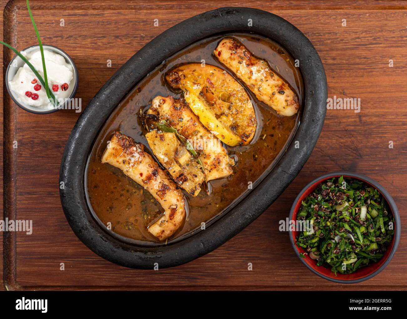 Polpo alla griglia con insalata di quinoa su piastra di pietra nera. Foto Stock