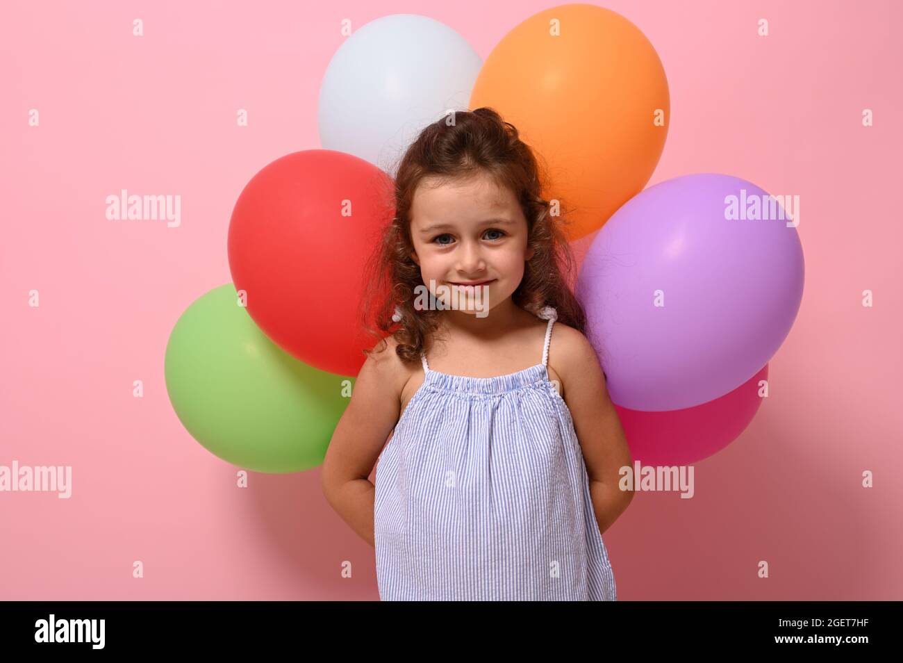 Ritratto sicuro di bello piccolo compleanno 4 anni ragazza che tiene  palloncini multicolore dietro la schiena e sorridente guardando la macchina  fotografica in posa contro pi Foto stock - Alamy