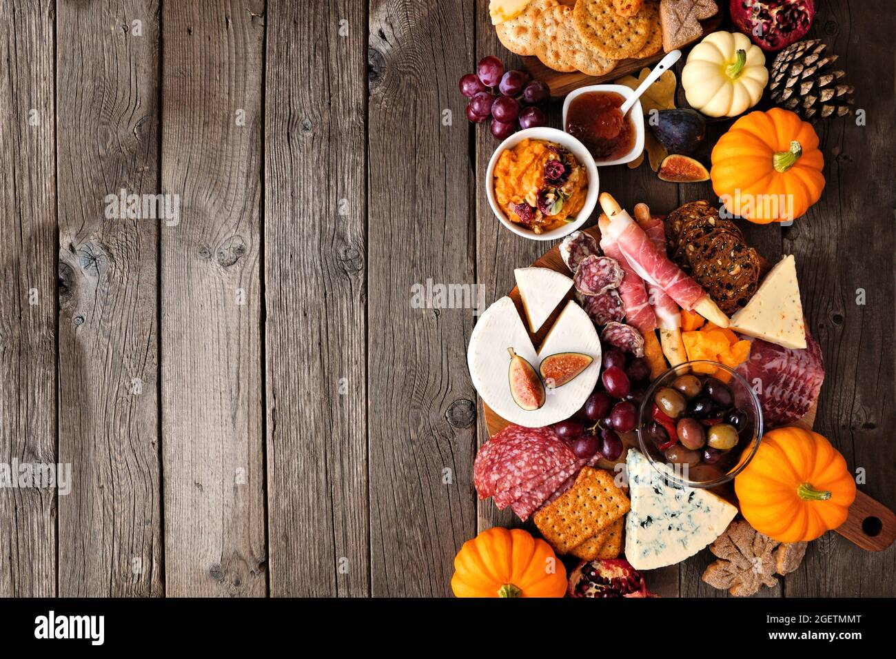 Tema autunno Charcuterie bordo laterale su uno sfondo di legno scuro. Selezione di formaggi e antipasti di carne. Spazio di copia. Foto Stock